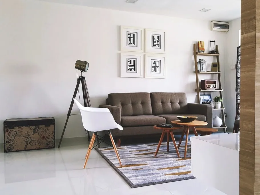 A bright living room with freshly painted white walls, a grey sofa and framed prints hung in a neat grid.