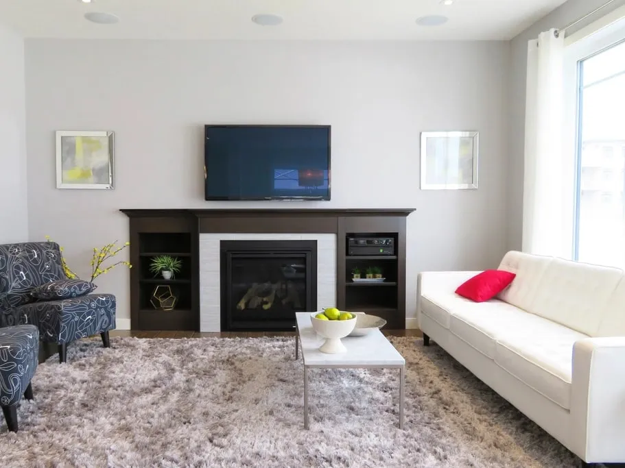 A living room painted in a warm white, with a fireplace surround and built-in shelving in a matching finish.